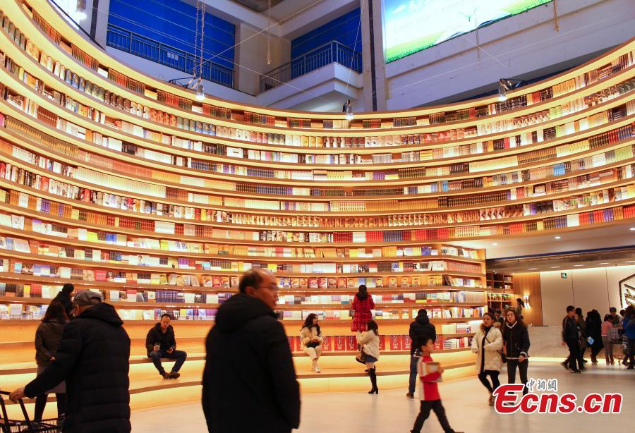 A circular wall stacked with books at a new bookstore in Hohhot, North China\'s Inner Mongolia Autonomous Region, Jan. 20, 2019. The innovative wraparound shelving units have attracted the interest of many visitors. (Photo: China News Service/Chen Feng)