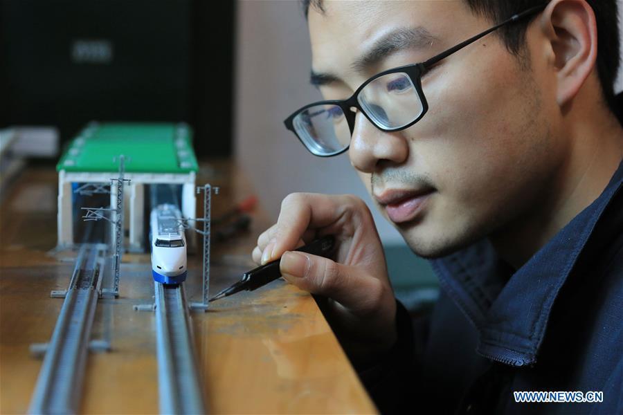 Zhang Yuqi makes a model of a bullet train maintenance center at his home in Guiyang, capital of southwest China\'s Guizhou Province, Jan. 30, 2019. As a model train hobbyist, 27-year-old Zhang Yuqi has made and collected more than a hundred model trains. Zhang is also a bullet train mechanic responsible for checking bullet trains during the Spring Festival travel rush at a maintenance center in Guiyang of Guizhou Province. Despite heavy work load and work pressure, Zhang said he is dedicated to ensuring the safety of bullet trains. (Xinhua/Ou Dongqu)