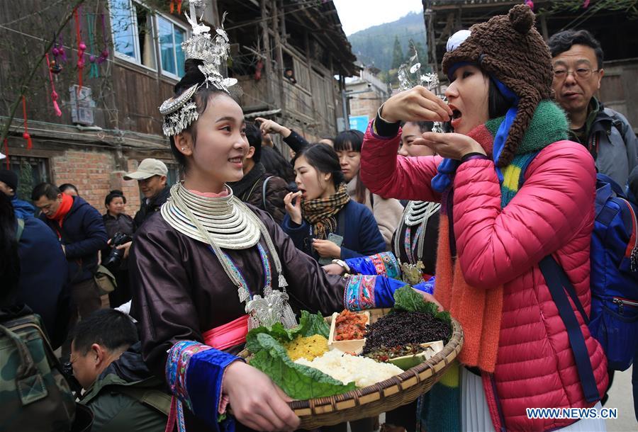 Tourists taste traditional food of Dong ethnic group during the Spring Festival holiday in Dingdong Village of Qiandongnan Miao and Dong Autonomous Prefecture, southwest China\'s Guizhou Province, Feb. 8, 2019. (Xinhua/Long Tao)