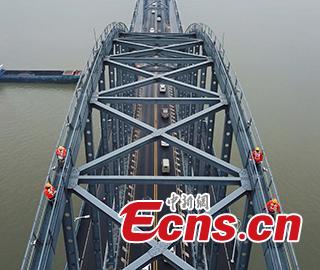 Technicians conduct a routine safety check on the Jiujiang Yangtze River Bridge, a major connection of the Beijing-Kowloon Railway in Jiujiang City, East China\'s Jiangxi Province during the travel peak of the Spring Festival. Despite the wind and vibration caused by the passing trains, they continued working in baskets hung under the bridge\'s girder, about 20 meters above the rolling Yangtze River. (Photo: China News Service/Ding Bo)