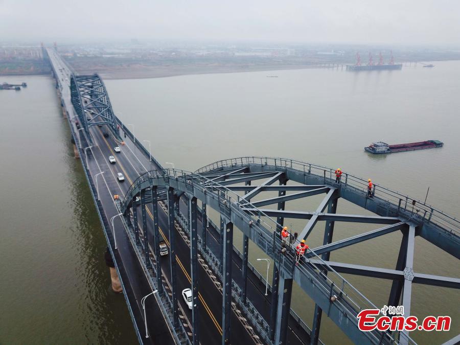 Technicians conduct a routine safety check on the Jiujiang Yangtze River Bridge, a major connection of the Beijing-Kowloon Railway in Jiujiang City, East China\'s Jiangxi Province during the travel peak of the Spring Festival. Despite the wind and vibration caused by the passing trains, they continued working in baskets hung under the bridge\'s girder, about 20 meters above the rolling Yangtze River. (Photo: China News Service/Ding Bo)