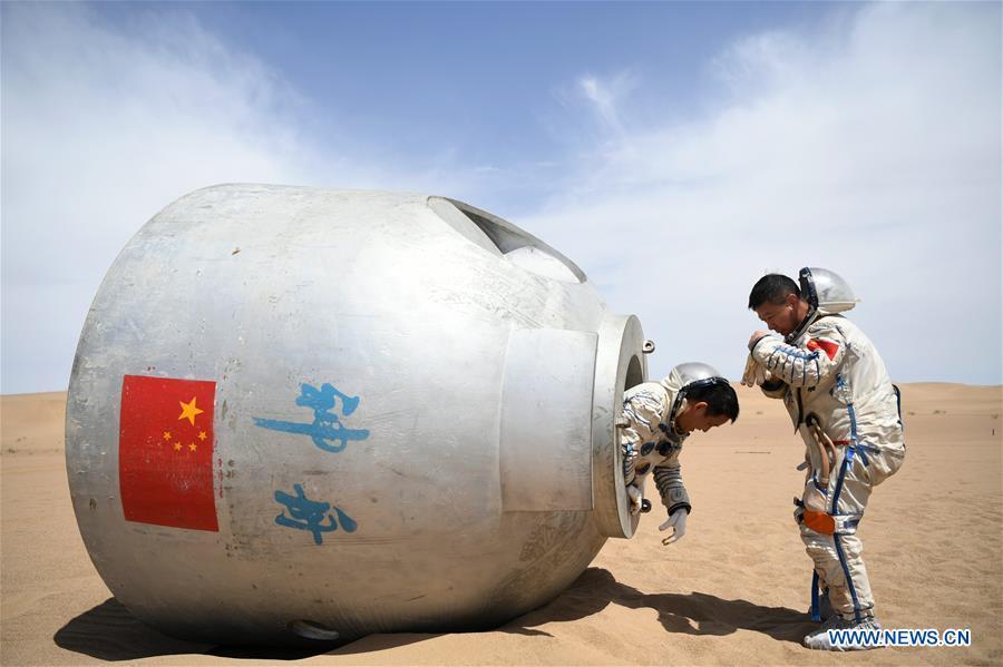 Taikonauts Nie Haisheng (L) and Liu Wang exit from a re-entry capsule during a wilderness survival training in the Badain Jaran Desert in northwest China\'s Gansu Province, May 17, 2018. The China Manned Space Engineering Office (CMSEO) announced Monday that the core module of the country\'s space station, the Long March-5B carrier rocket and its payloads will be sent to the launch site in the second half of this year, to make preparations for the space station missions. China is scheduled to complete the construction of the space station around 2022. It will be the country\'s space lab in long-term stable in-orbit operation. (Xinhua/Chen Bin)