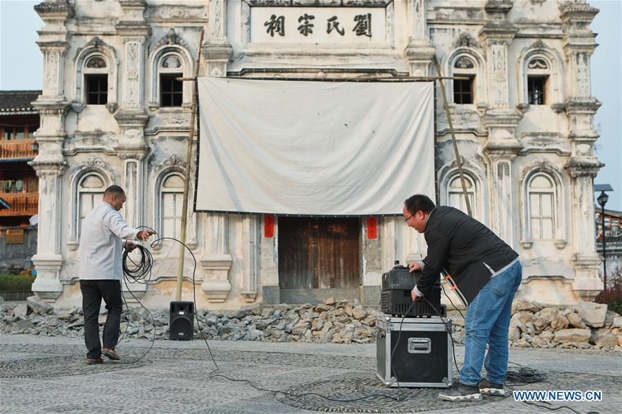 Huang Yiyin (1st R) and his assistant Wang Yangqing (1st L) prepare the screening facilities in Santangmen Village of Benchu Town, Tianzhu County of Miao and Dong Autonomous Prefecture of Qiandongnan, southwest China\'s Guizhou Province, March 19, 2019. Local authority in Tianzhu County established special fund to show movies in rural areas. In 2018, a total of 14 voluntary projectionists in Tianzhu showed 3,979 movies in villages within the county. (Xinhua/Ou Dongqu)