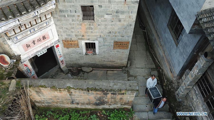 Aerial photo shows Huang Yiyin (front) and his assistant Wang Yangqing carrying the screening facilities in Santangmen Village of Benchu Town, Tianzhu County of Miao and Dong Autonomous Prefecture of Qiandongnan, southwest China\'s Guizhou Province, March 19, 2019. Local authority in Tianzhu County established special fund to show movies in rural areas. In 2018, a total of 14 voluntary projectionists in Tianzhu showed 3,979 movies in villages within the county. (Xinhua/Ou Dongqu)