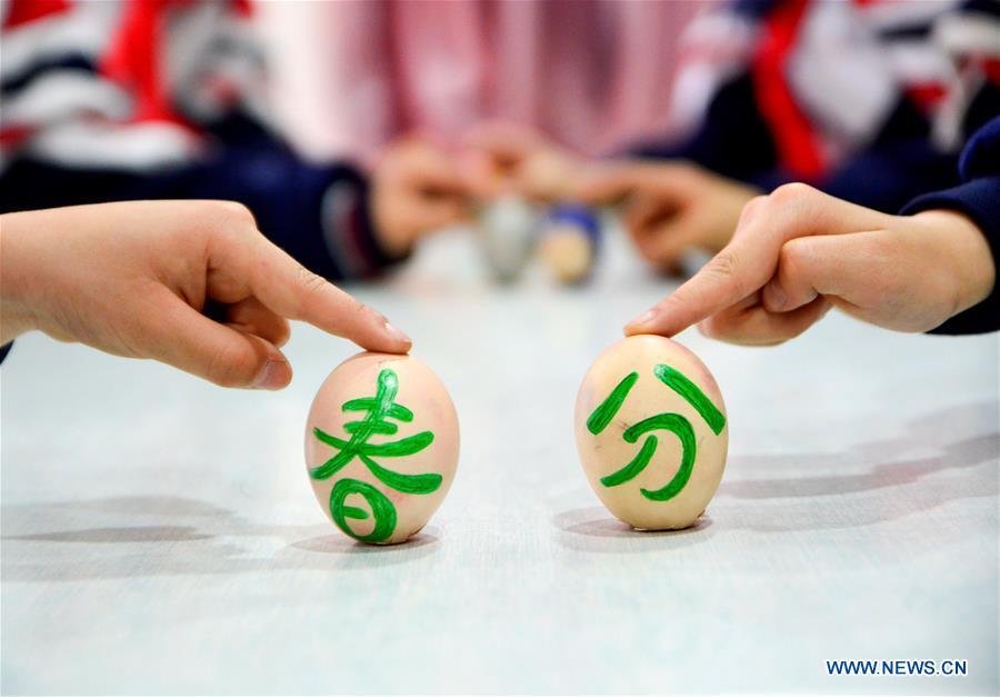 Students play a game to make eggs stand upright on end at a primary school in Handan, north China\'s Hebei Province, March 20, 2018, one day ahead of \