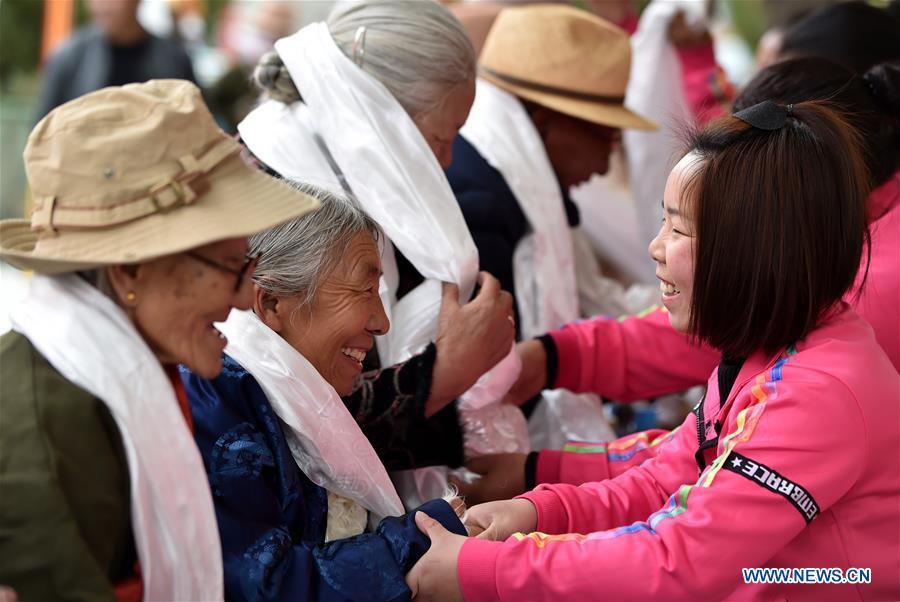 Young people present hada, a white ceremonial silk scarf, to the elderly in an event to celebrate the 60th anniversary of democratic reforms in Tibet, at a community in Lhasa, capital of southwest China\'s Tibet Autonomous Region, March 23, 2019. (Xinhua/Chogo)