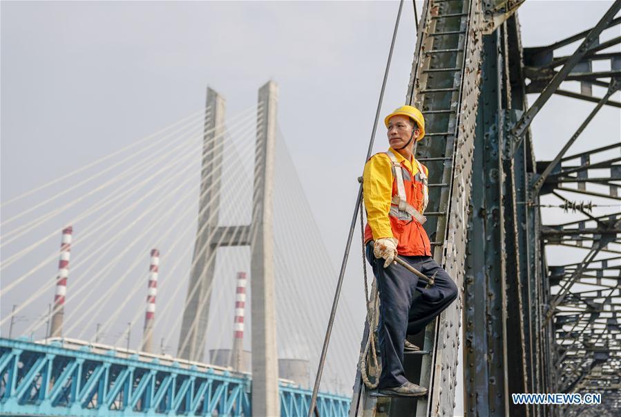 Tang Jinhua looks at the new Baishatuo Yangtze River railway bridge in Jiangjin of southwest China\'s Chongqing Municipality, April 23, 2019. The previous Baishatuo Yangtze River railway bridge, completed in 1959, will stop service after April 24. All trains will run on the new double decker steel truss cable stay railway bridge after that day. The new bridge has 4 tracks on the upper deck for passenger trains with a designed speed of 200 kilometers per hour and 2 tracks on the lower deck for cargo trains with the designed speed of 120 kilometers per hour. (Xinhua/Liu Chan)