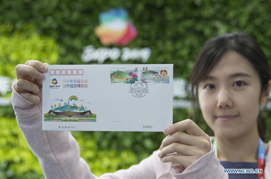 A journalist shows a first-day cover with commemorative stamps issued to mark the International Horticultural Exhibition 2019 Beijing at the media center in Yanqing District of Beijing, capital of China, April 29, 2019. Beijing Stamp Company issued the first-day cover with a set of two commemorative stamps on Monday. (Xinhua/Hou Dongtao)