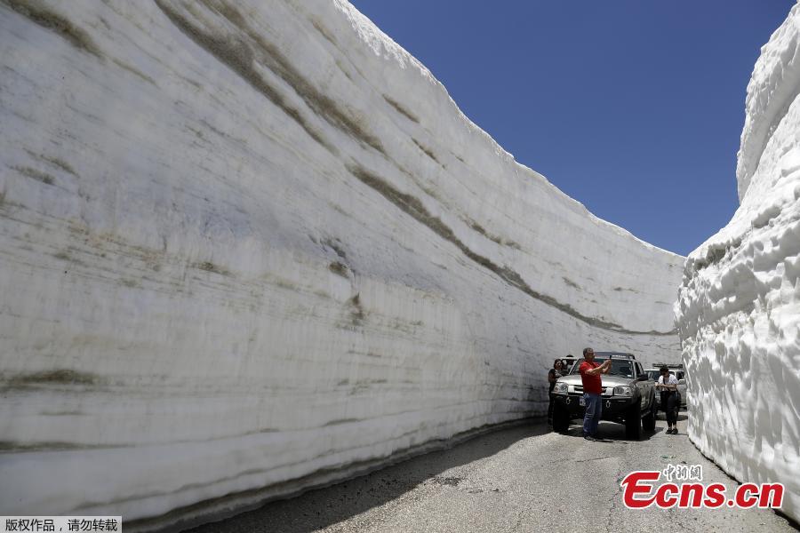 People take pictures on a road, surrounded by walls of snow, on May 28, 2019, in the northern Lebanese village of Ainata al-Arz, 1,620 meters above sea level.(Photo/Agencies)