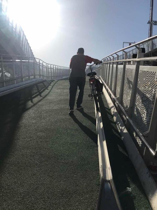 A cyclist walks with his bike up the slope on the first bicycle-only lane in Beijing, May 31, 2019. (Photo/chinadaily.com.cn)